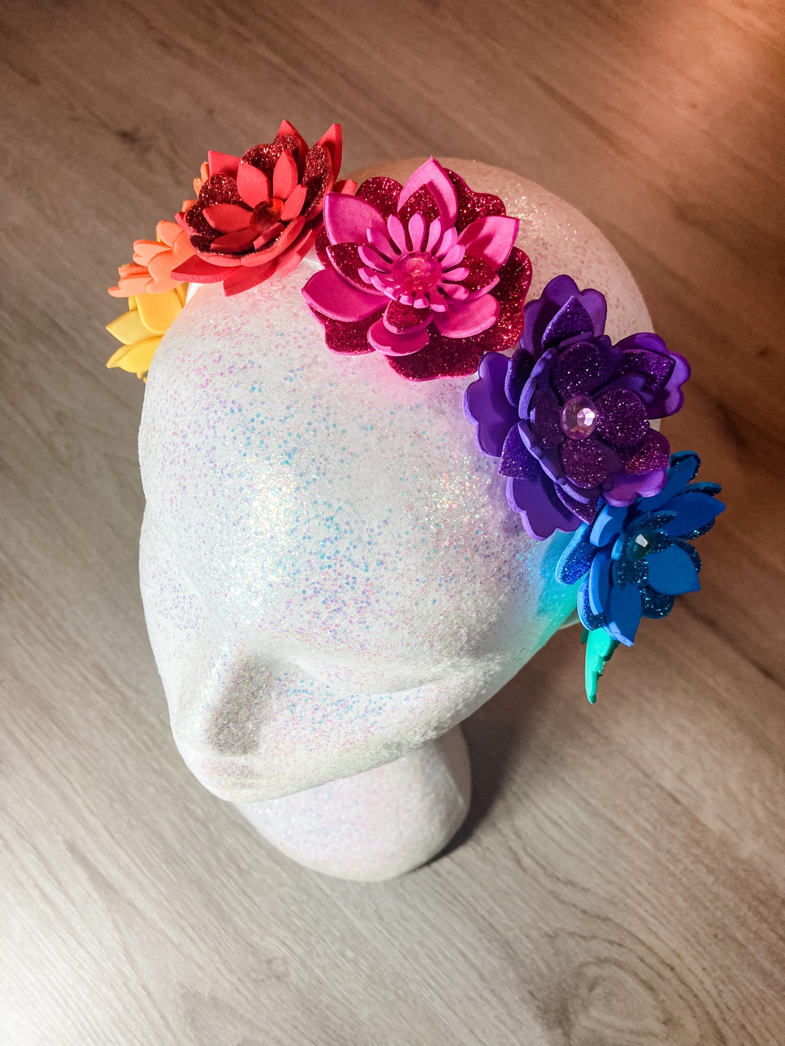 Mannequin head with colorful flower accessories on a wooden surface
