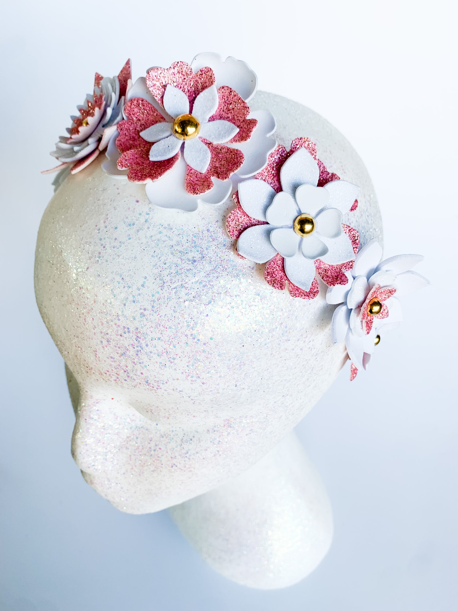Decorative headband with pink and white flowers on a mannequin head against a light background