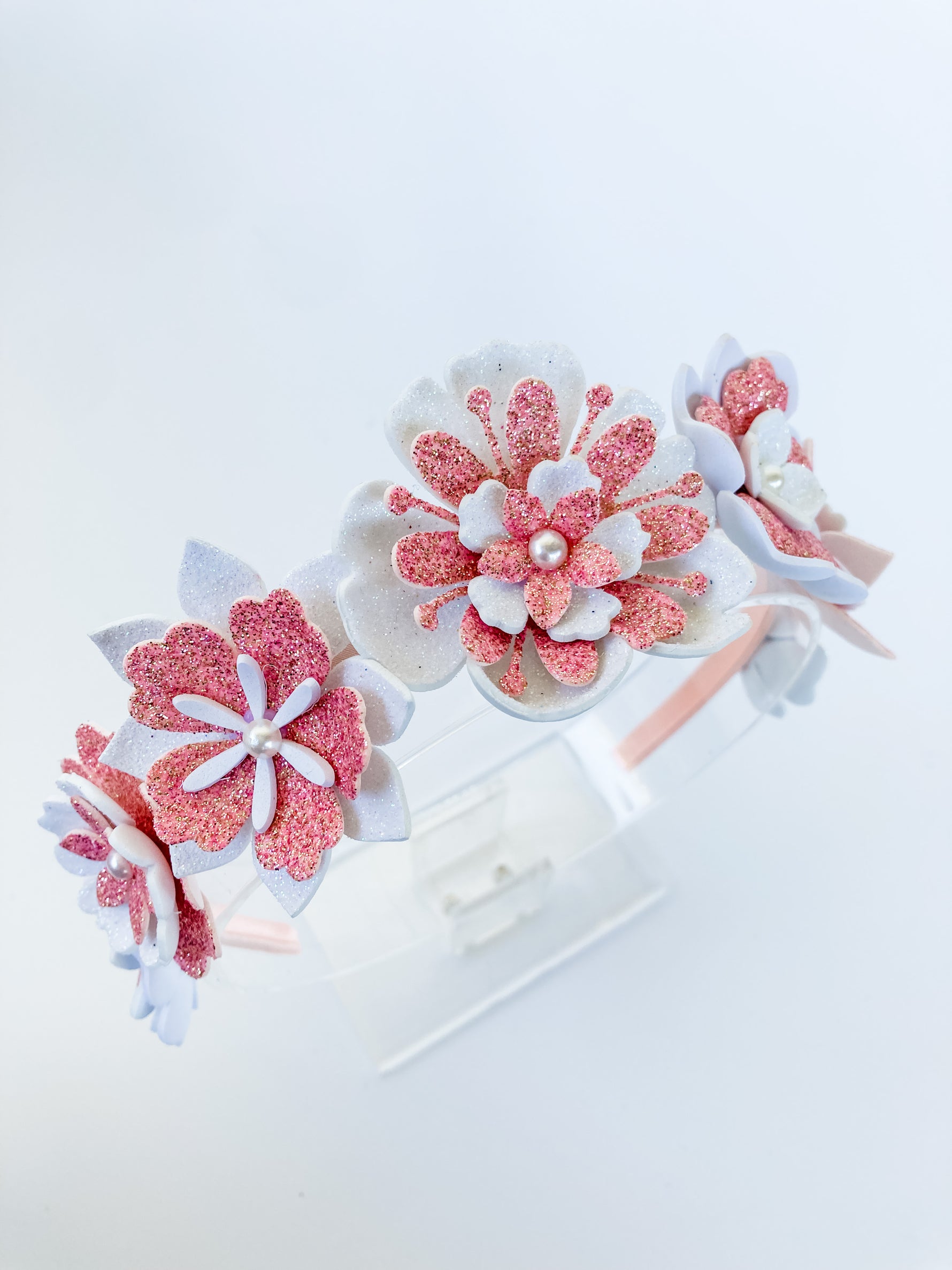 Decorative headbands with pink and white floral designs on a white background