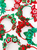A variety of Green, red and gold glitter floral headbands with green or red glitter tiaras. Flowers have layers of petals and diamonte centres. 