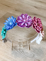 Colorful flower headband on a clear stand with a wooden background