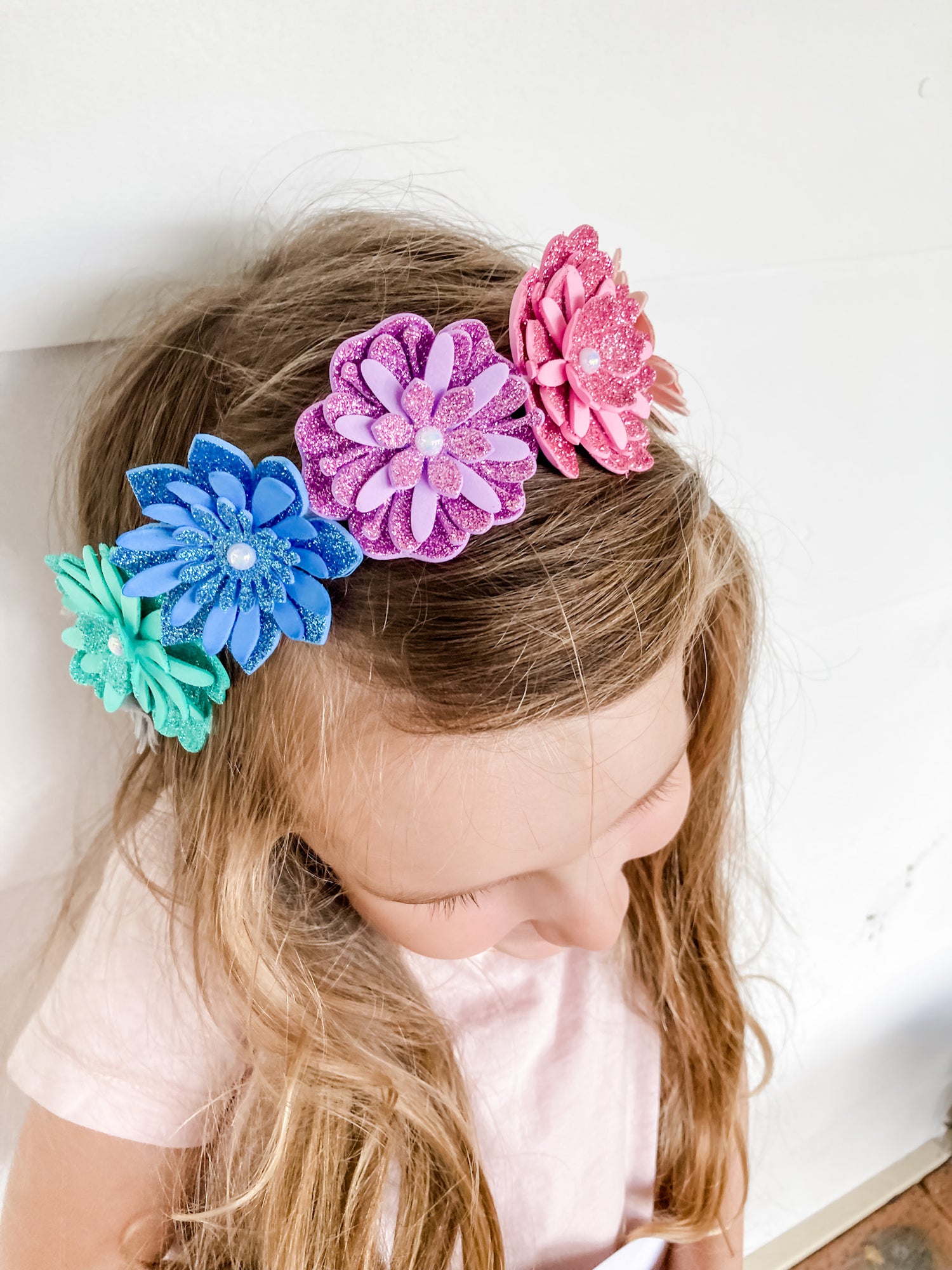 Child wearing colorful flower headbands on a white background