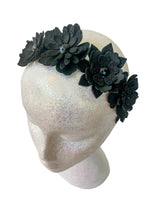 Black floral headband on a mannequin head against a white background