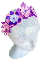 Decorative headband with pink and purple flowers on a mannequin head against a white background