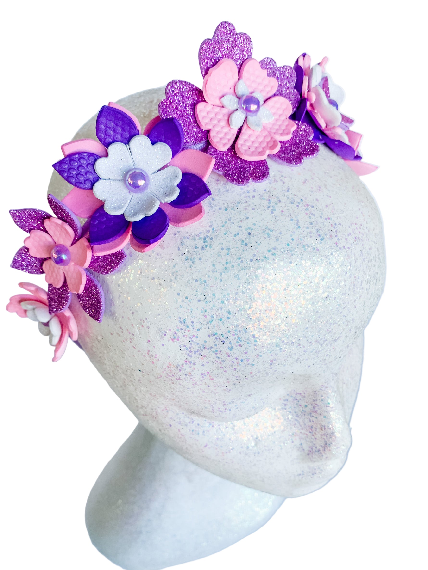 Decorative headband with pink and purple flowers on a mannequin head against a white background
