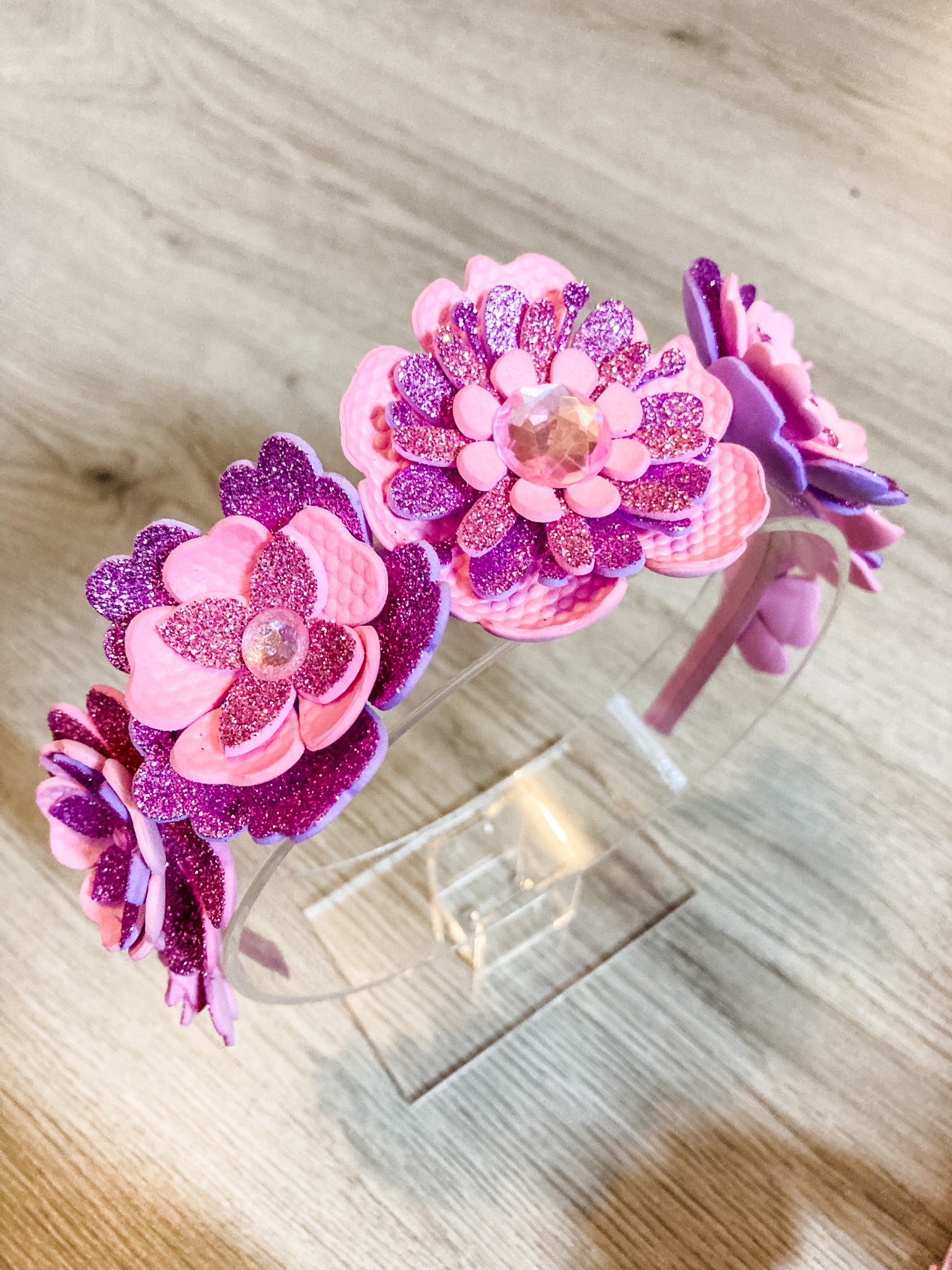 Two pink and purple flower-shaped hair clips on a wooden surface