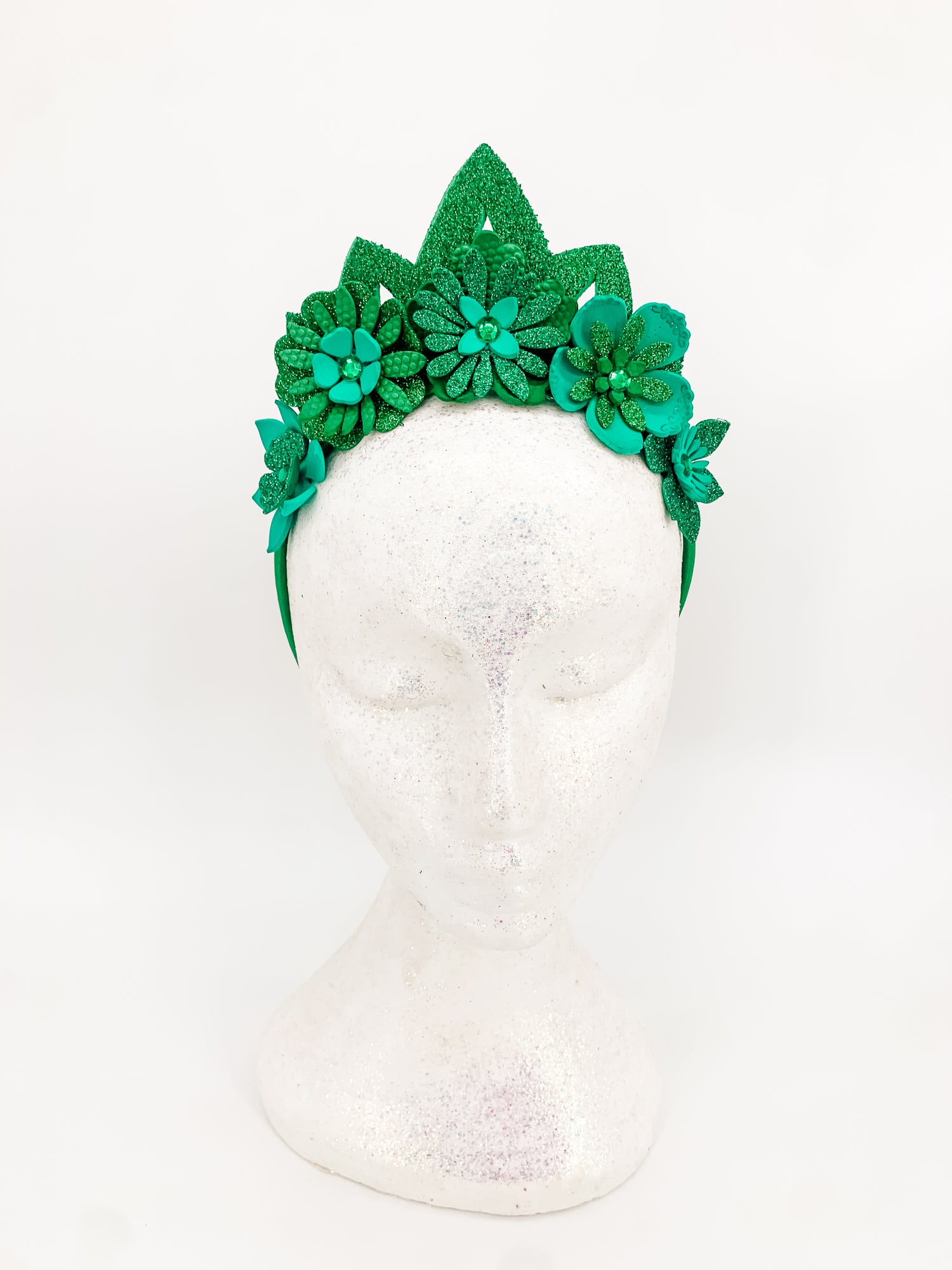 Green glitter floral headband with green glitter tiara. Flowers have layers of petals and diamonte centres on a white glitter display head