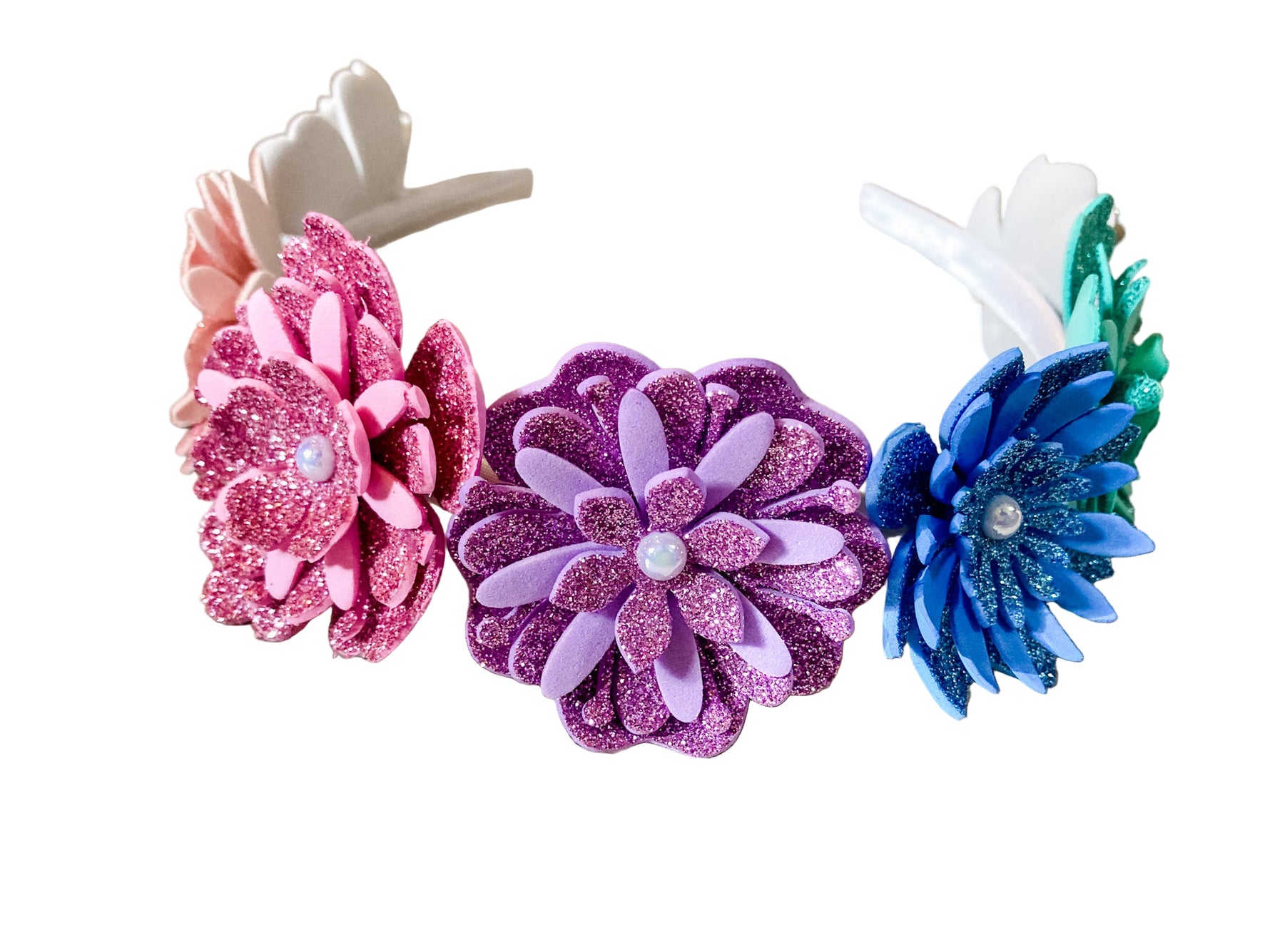 Three colorful flower headbands on a wooden surface