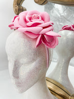 Baby pink roses and buds made of soft foam shaped across a headband fascinator. Displayed on a glitter white mannequin head with an ornate gold mirror behind. 