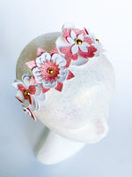 Decorative headband with pink and white flowers on a mannequin head against a light background