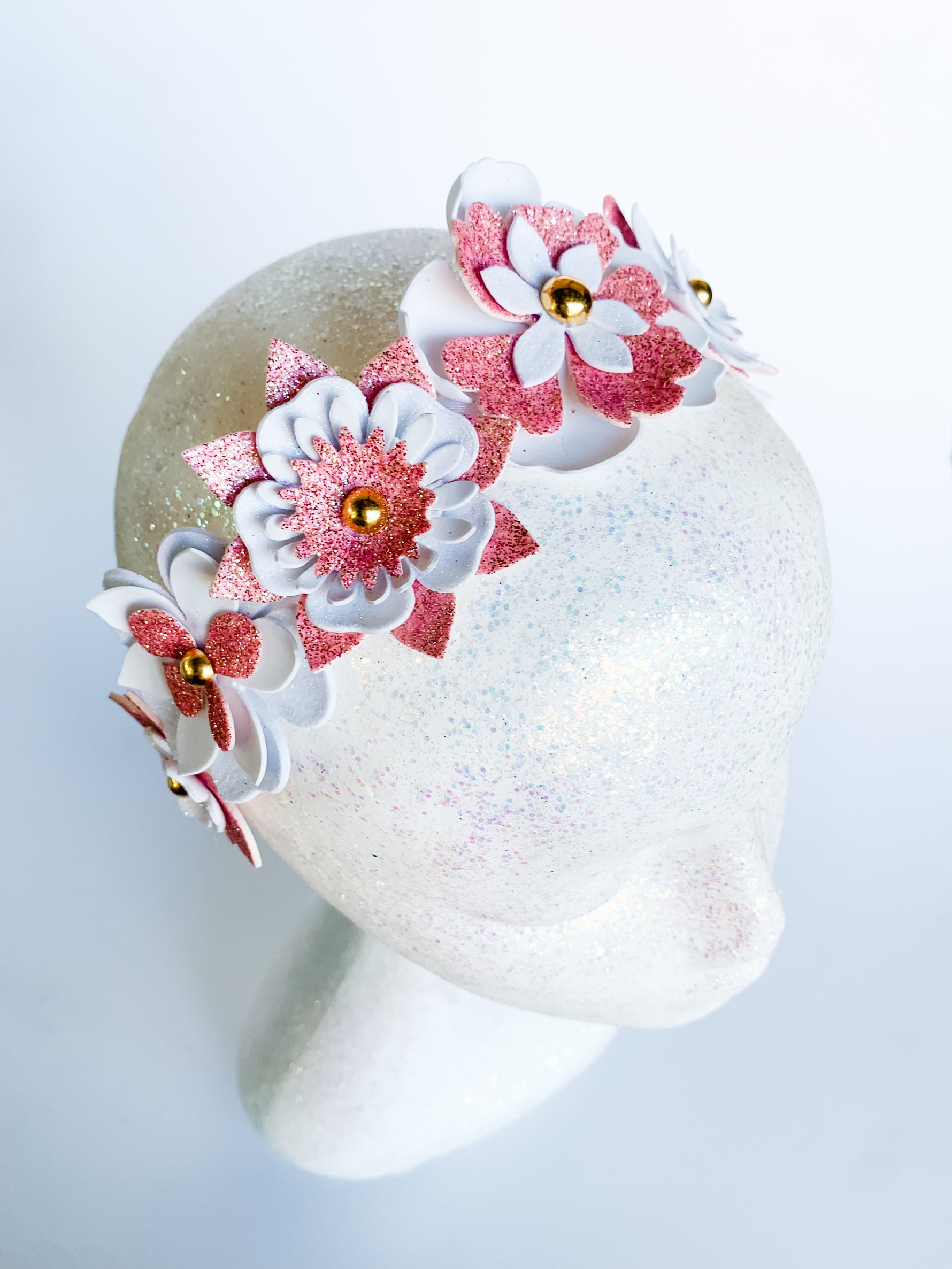 Decorative headband with pink and white flowers on a mannequin head against a light background