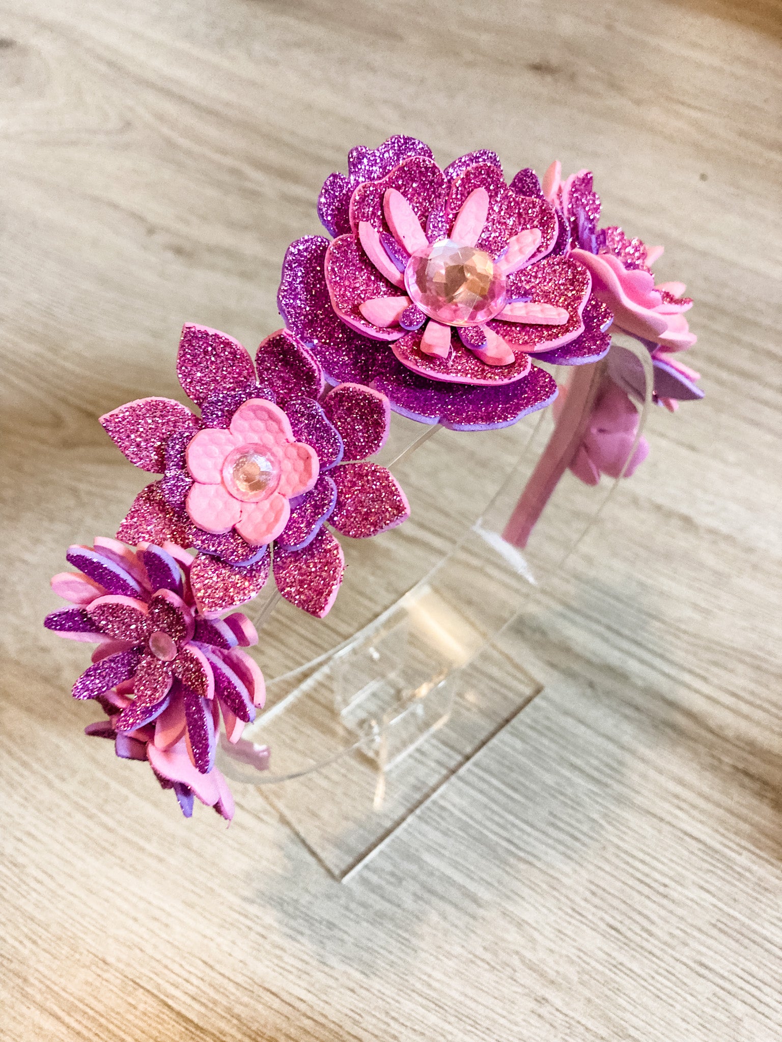 Two pink and purple flower-shaped hair accessories on a wooden surface.
