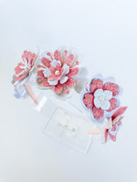 Set of pink and white floral hair accessories on a light background