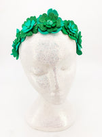 Green glitter floral headband with layers of petals and diamonte centres on a white glitter display head