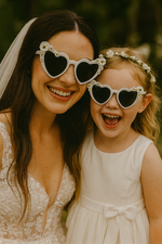 Woman and young girl wearing heart-shaped sunglasses outdoors
