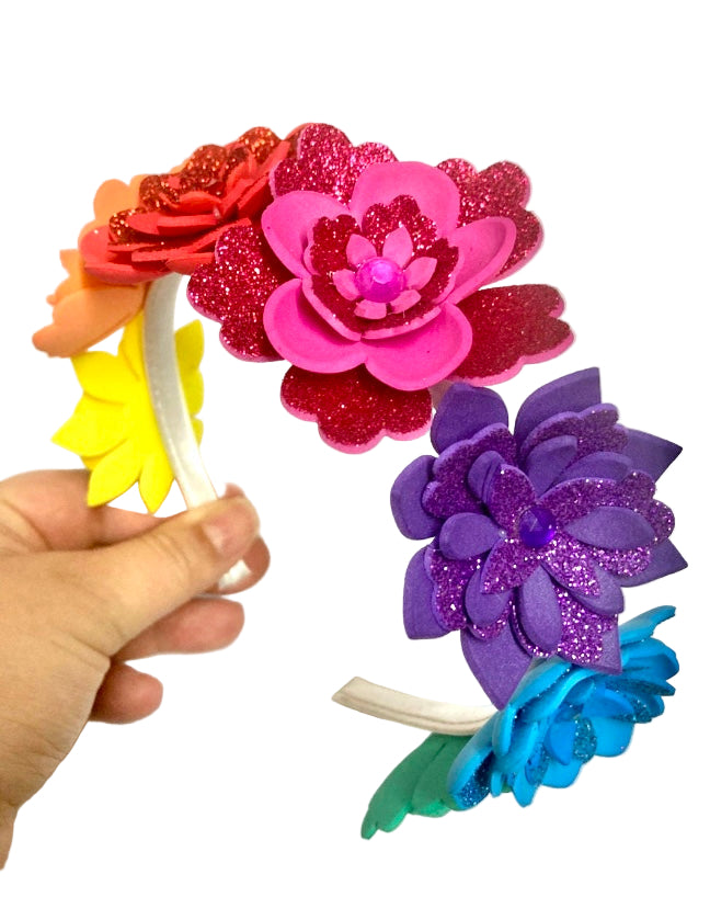 Colorful flower-shaped hair accessories held by a hand against a white background.