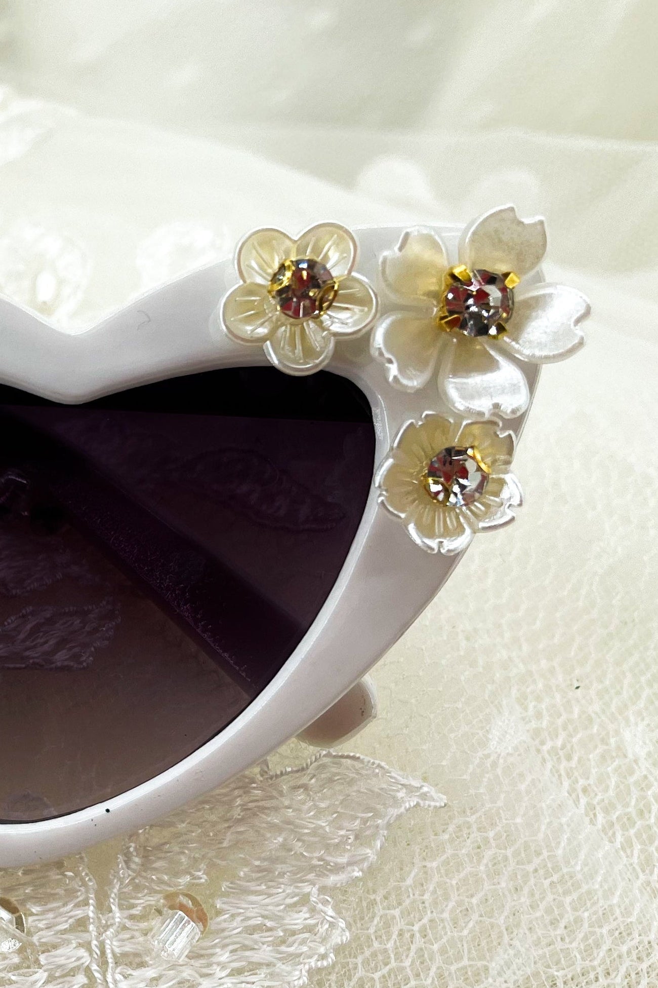 Heart-shaped sunglasses with floral decorations on a lace background