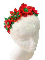 Red and green floral headband on a mannequin head with a white background